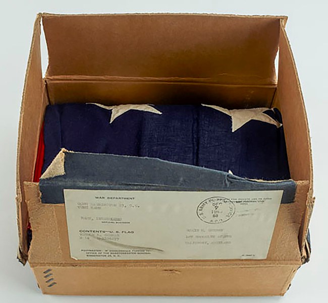 Burial flag of 2nd Lt. Vernon German, killed during the Battle of the Bulge on December 23, 1944. Collection of the Smithsonian National Museum of American History (2010.0058.01). Color photo of a folded American flag resting in its original cardboard shipping box.