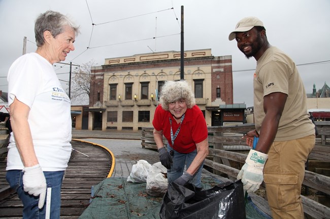 Olf with volunteers CVA Olf smiling with two other ladies while picking up trash by some train tracks