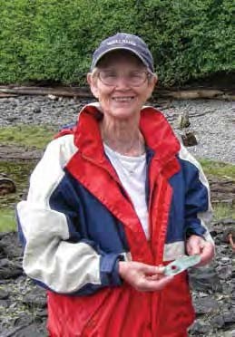 A person poses for the camera holding an artifact