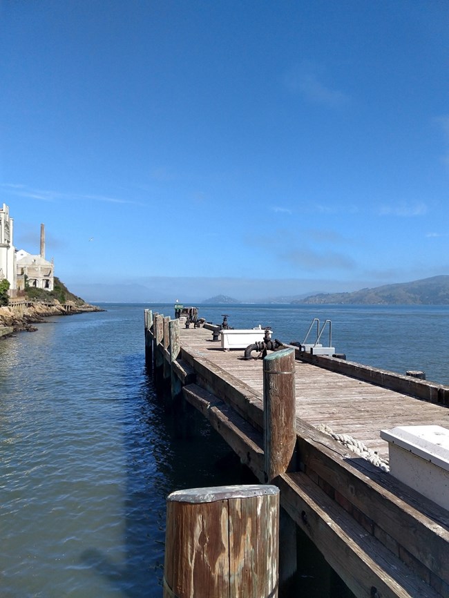 Alcatraz Island finger pier jutting out into bay with historic buildings on left. Alcatraz Island finger pier jutting out into bay with historic buildings on left.